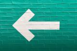 A white arrow on a blue brick wall
